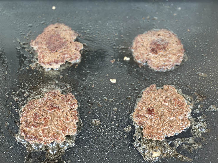four smashed burger patties on the griddle