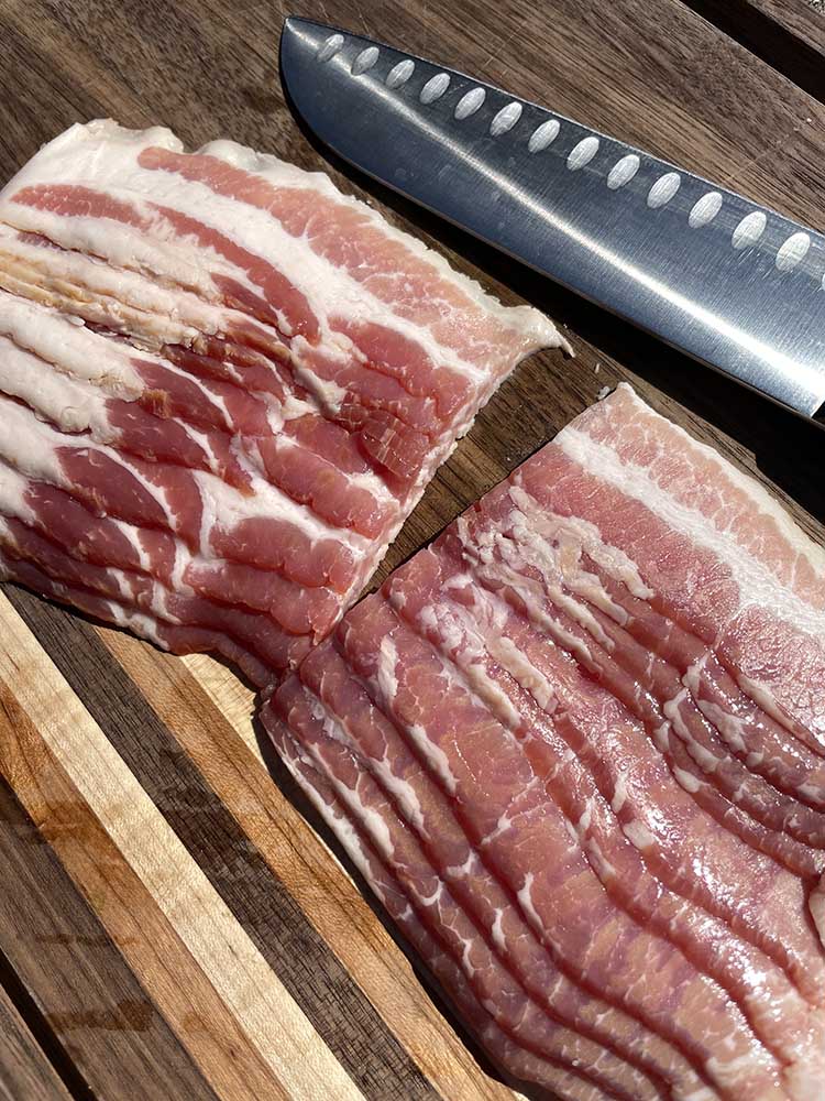 thick cut bacon sliced in half on a wooden board
