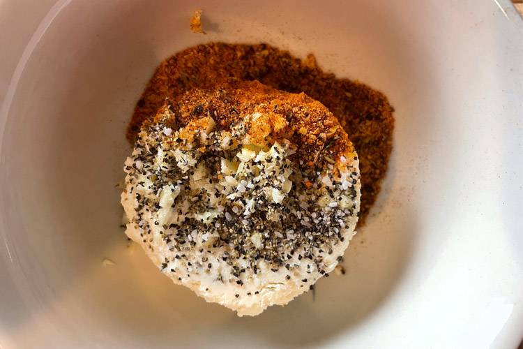 Boursin cheese in a bowl with salt, pepper, and bbq rub