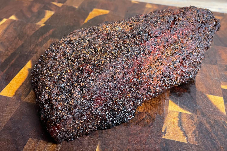 cooked smoked pastrami on a wooden chopping board