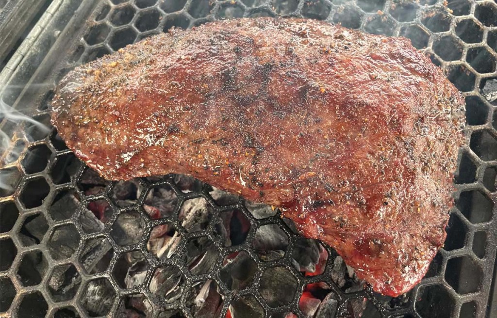 grilled flat iron steak on wire rack over coals