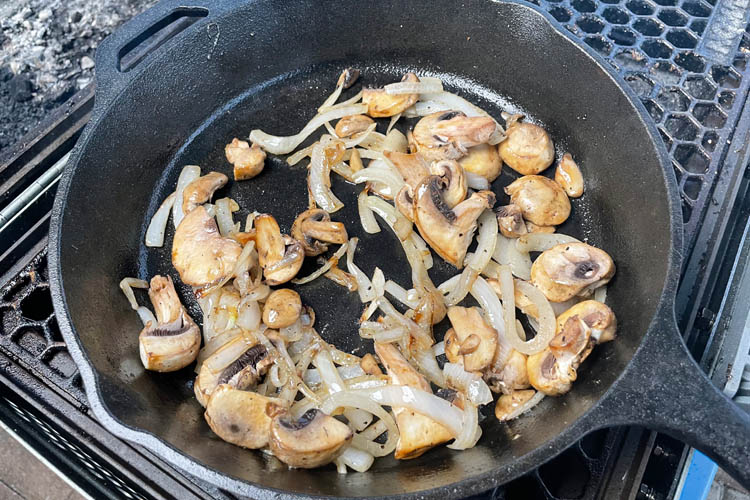 sliced onions and mushrooms in a skillet on the grill