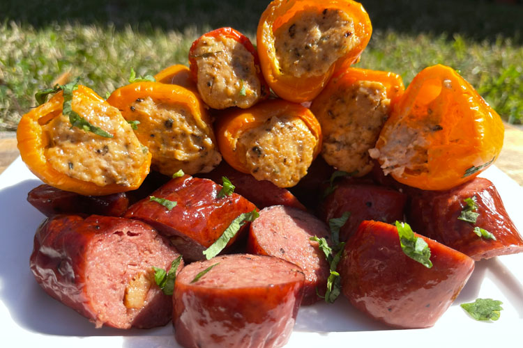 cooked peppers and sliced up sausage on a white plate