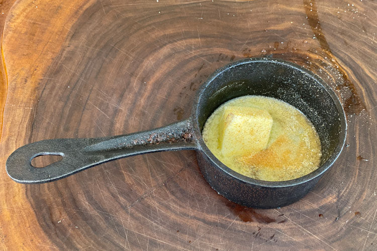 cast iron pot with butter on a wooden chopping board