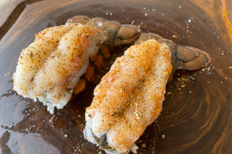 seasoned lobster tails on wooden chopping board