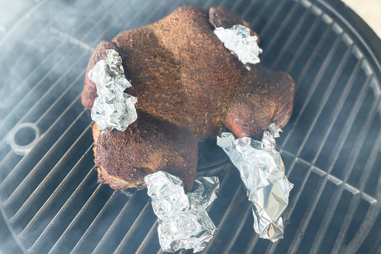 chicken on the grill with foil on its tips