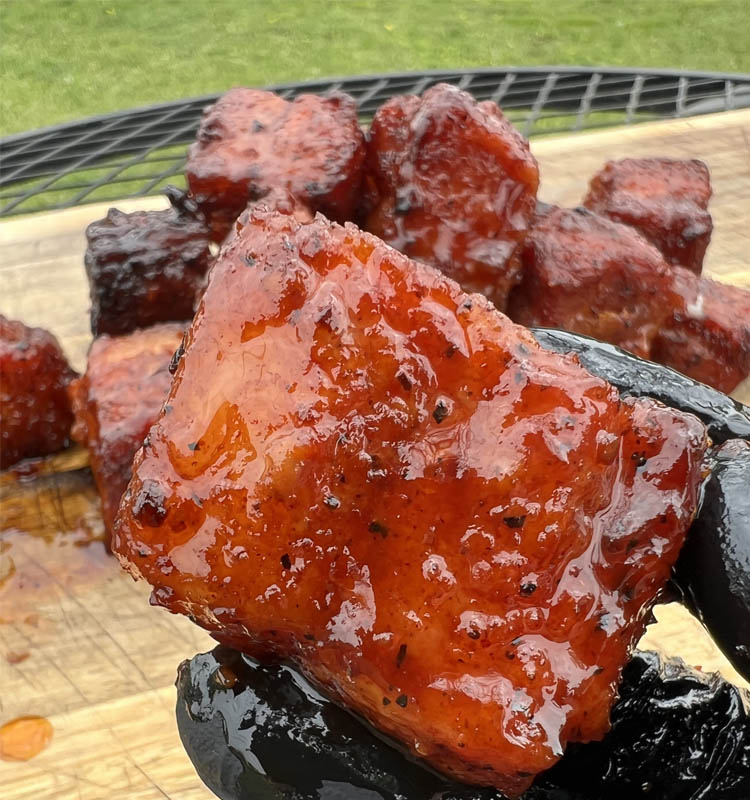 black gloved hand holding a pork cube