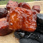 holding pork belly burnt ends in gloved hand