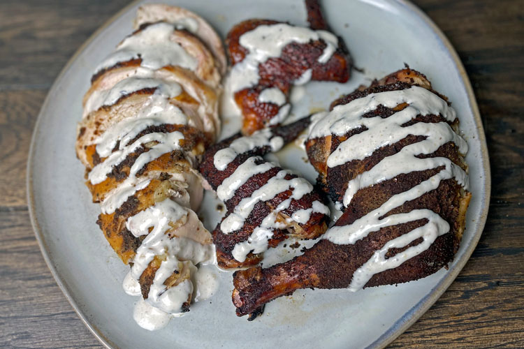chicken pieces drizzled with alabama white sauce on a white plate