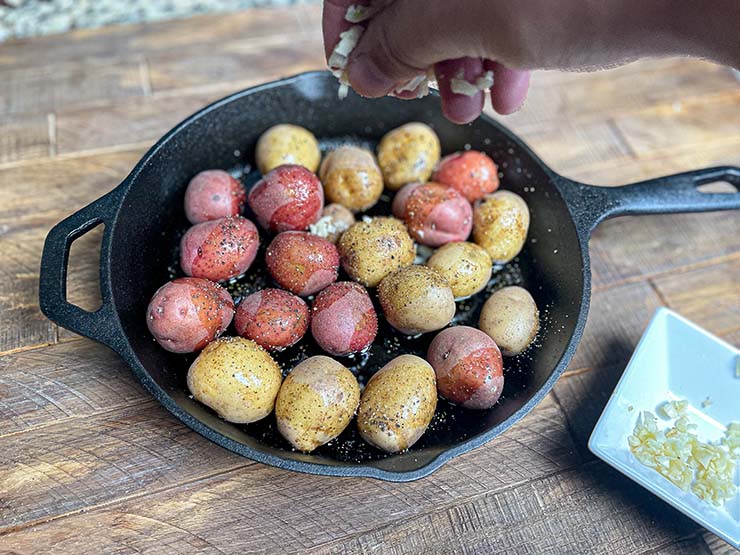 baby potatoes on a skillet with added chopped garlic