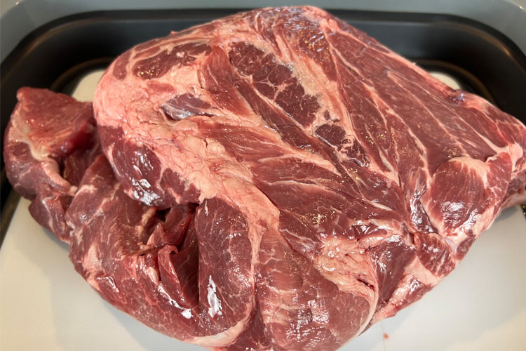 raw chunk of pork butt on white board