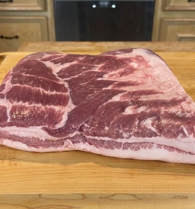 whole piece of pork belly on a wooden board