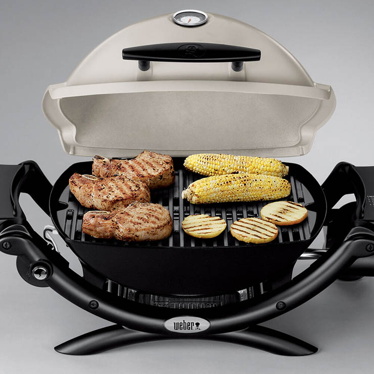 Weber Q1200 gas grill with meats and veggies on grill grates