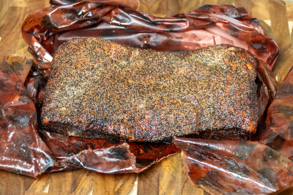 a piece of cooked pork belly sitting on the pink butcher paper it was wrapped in