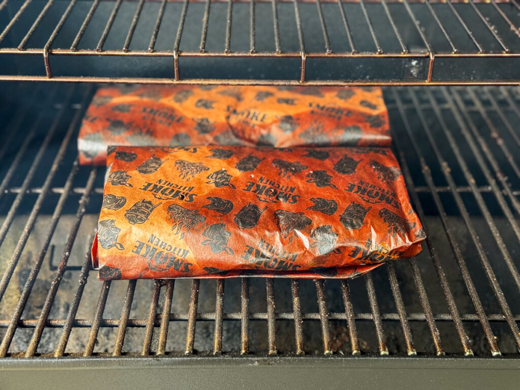 pork belly wrapped in pink butcher paper near the end of the cook