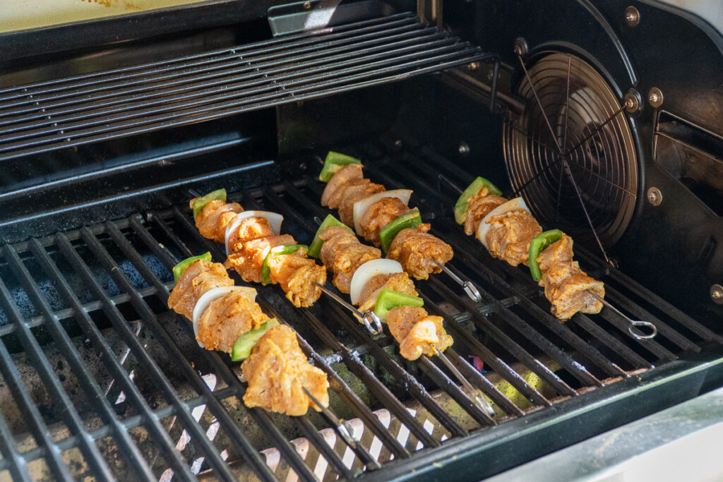 five raw chicken skewers on the grill