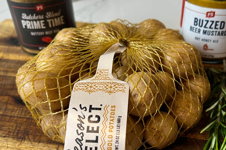 raw potatoes in a mesh bag on a wooden chopping board