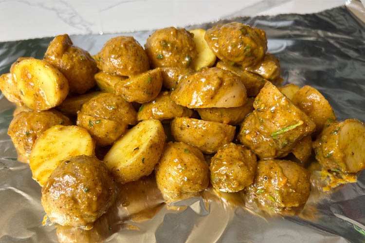 mustard coated potatoes on a sheet of aluminum foil