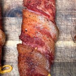 smoked cheddar cheese stuffed bacon wrapped brat on a wooden table