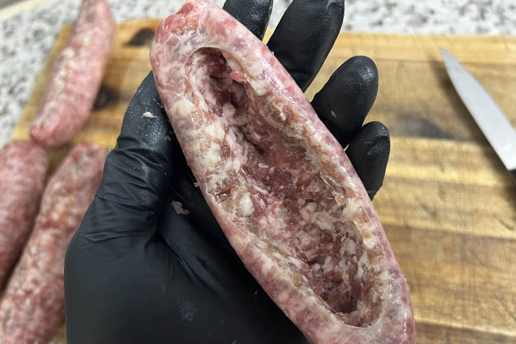 a black gloved hand holding a hollowed out brat