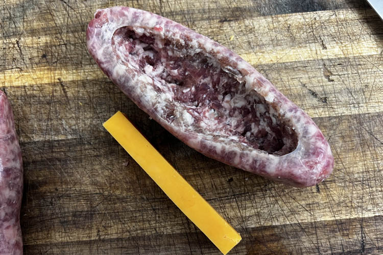 Cut brat and slice of cheddar on wooden board