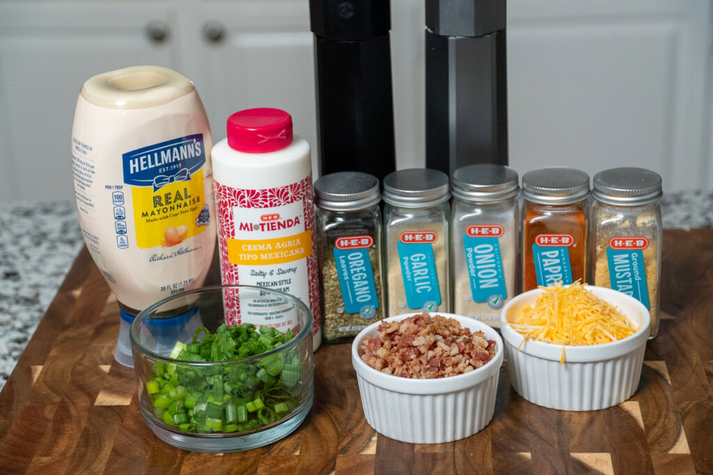 the ingredients for loaded potato salad laid out ona wooden board