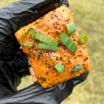 gloved hand holding smoked salmon burn end
