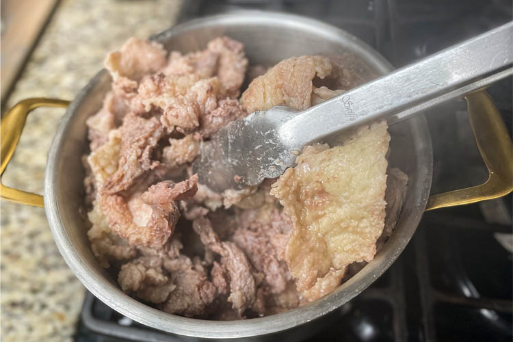 rendered fat in stockpot being stirred with tongs