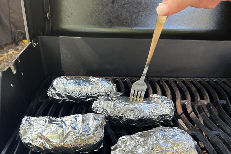 a fork piercing a potatoe on the grill