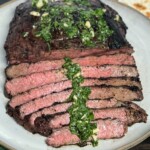 sliced grilled skirt steak topped with cilantro-lime marinade on a white plate