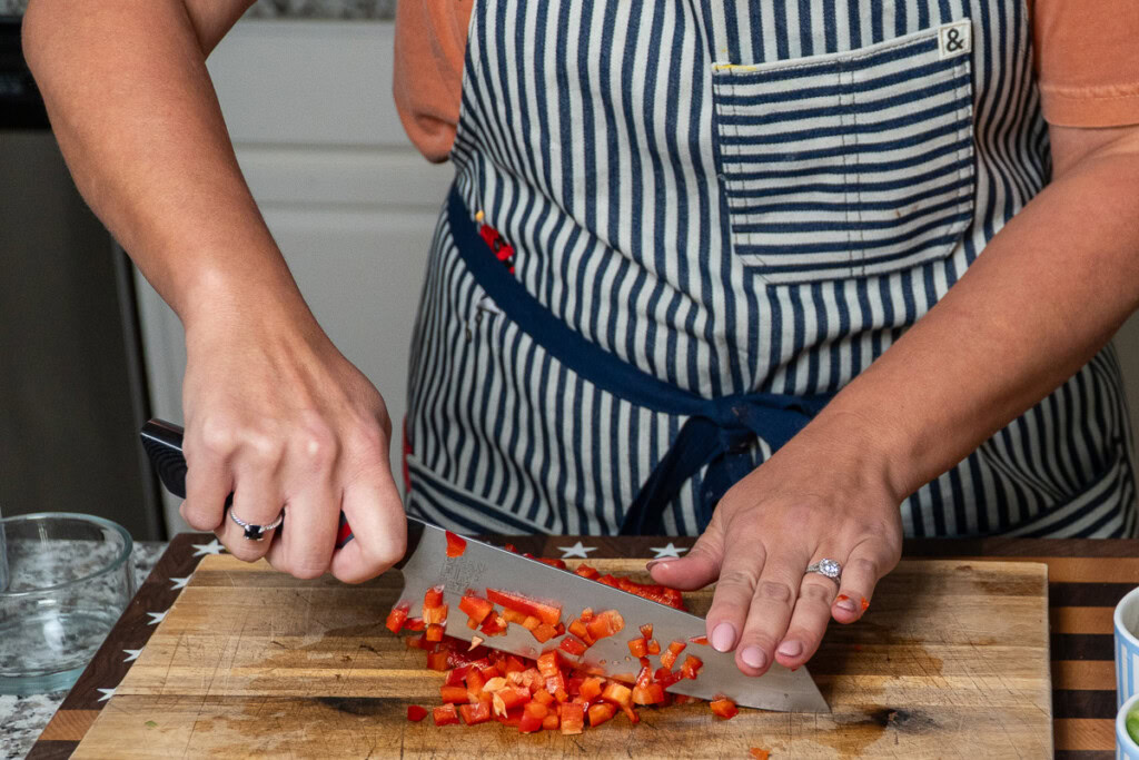 a person dicing red pepper