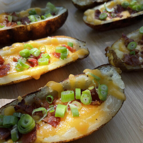loaded potatoe skins on a wooden chopping board