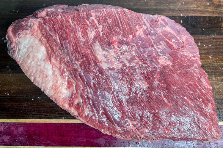 raw brisket on wooden chopping board