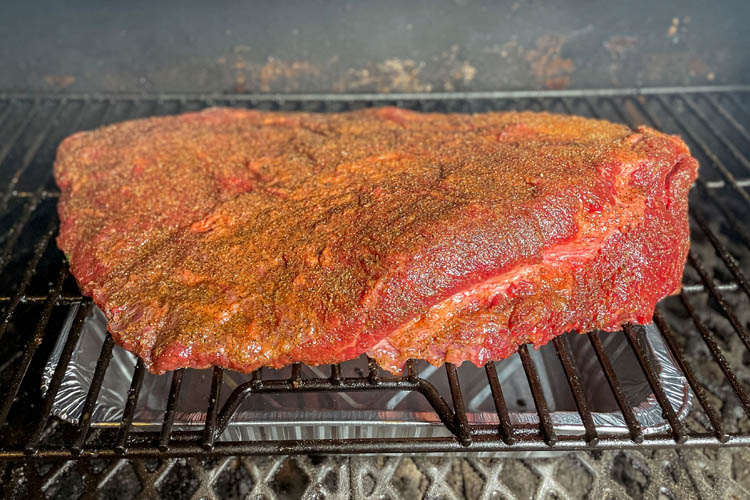 raw seasoned brisket on the grill