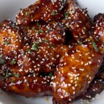 smoked and fried chicken wings covered in honey garlic sauce on a white plate