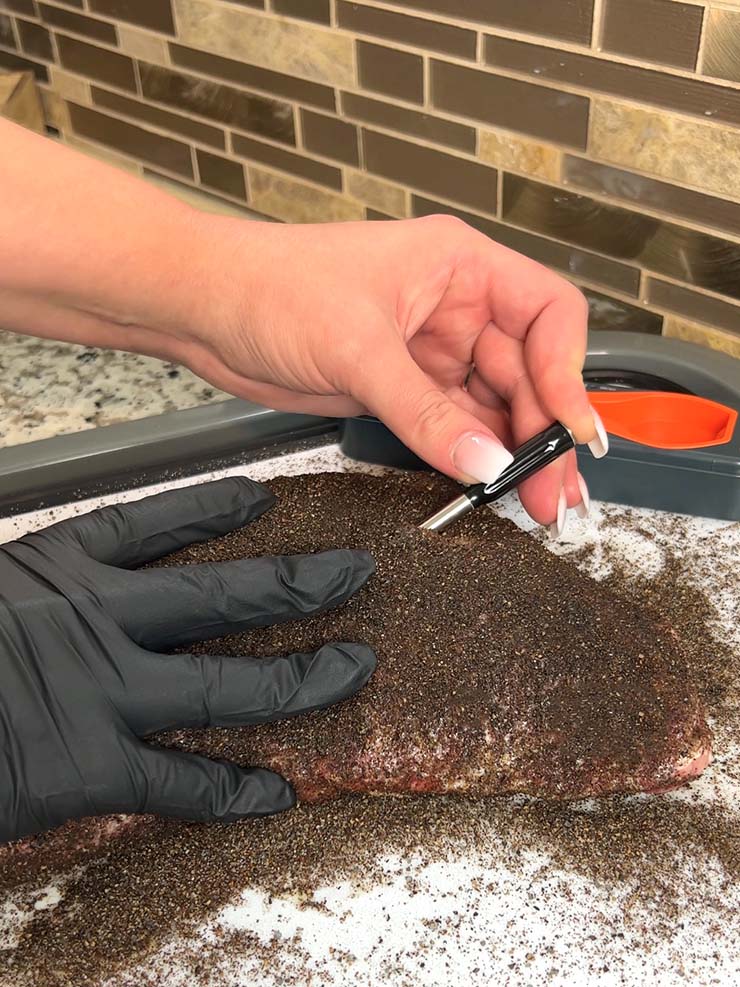 a woman inserting ThermoPro TempSpike probe into a piece of meat