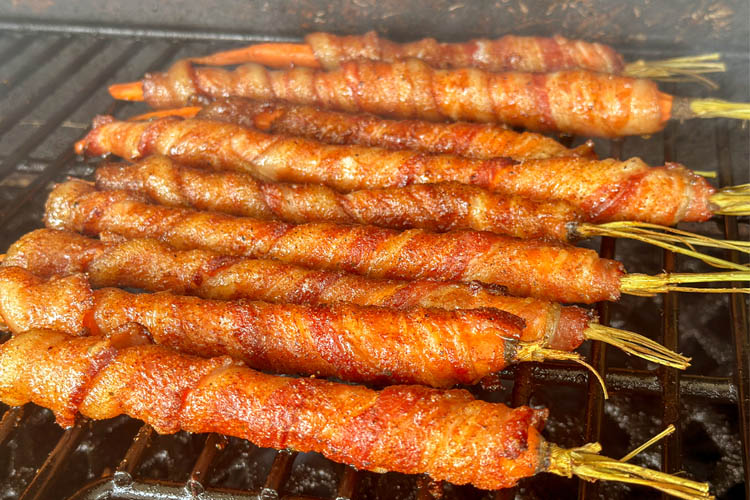 bacon wrapped carrots cooking on the grill