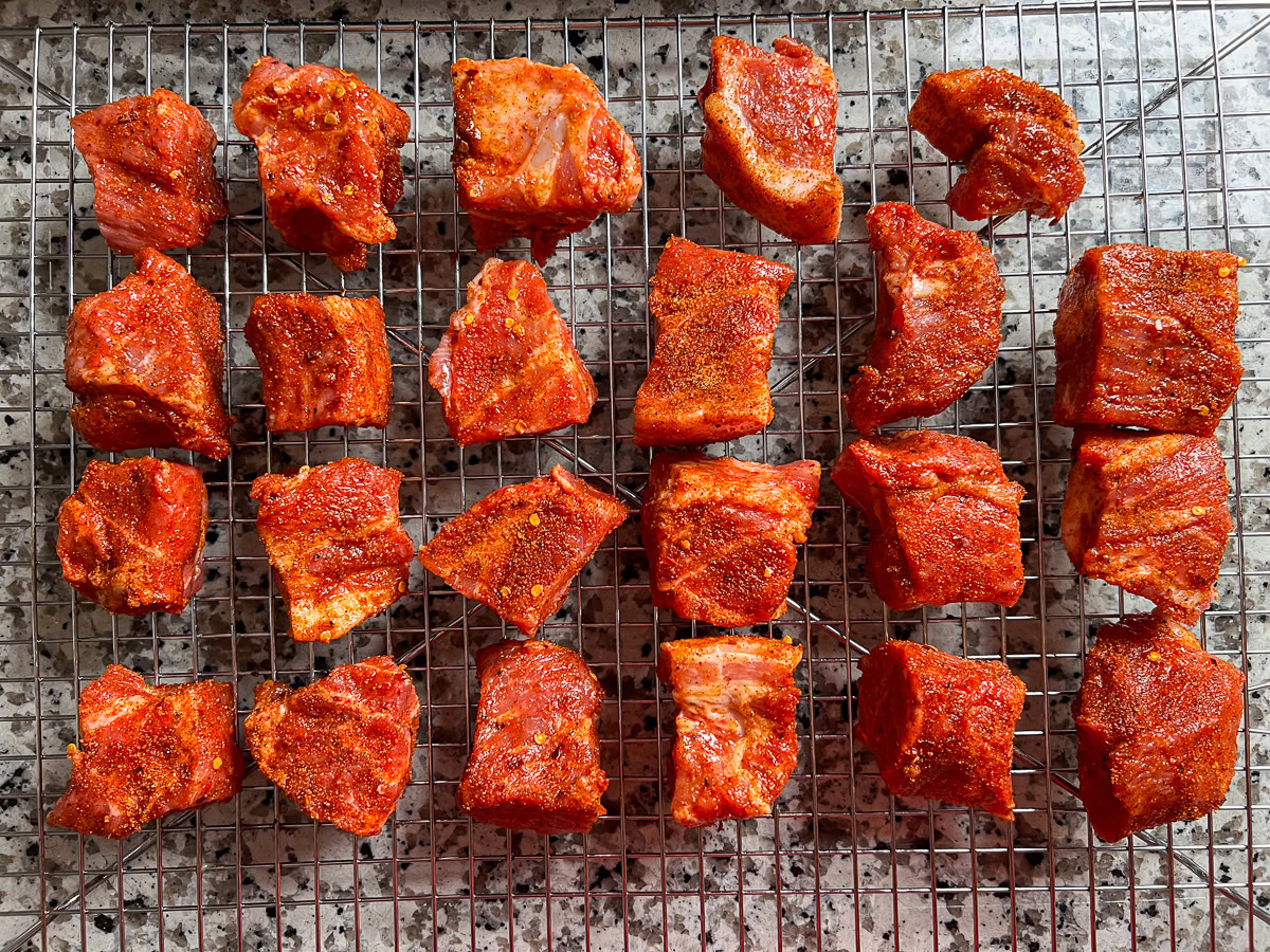 Pork cubes coated in BBQ rub on a tray, ready to smoke.