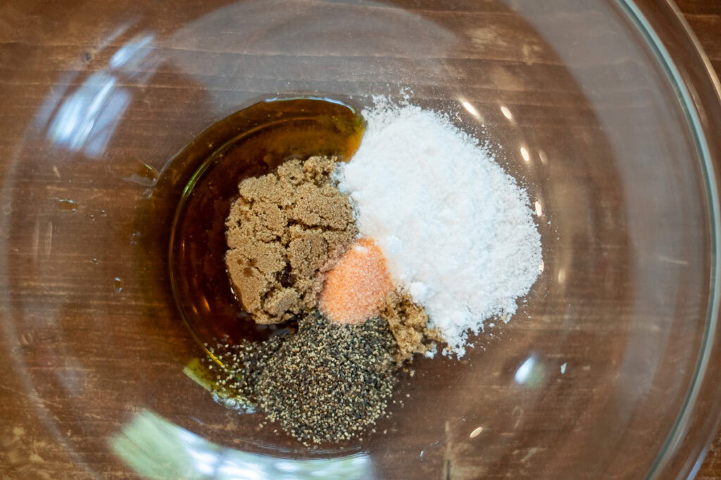 Dry and wet cure ingredients including brown sugar, kosher salt, Prague Powder #1, maple syrup, and black pepper arranged in a glass mixing bowl.