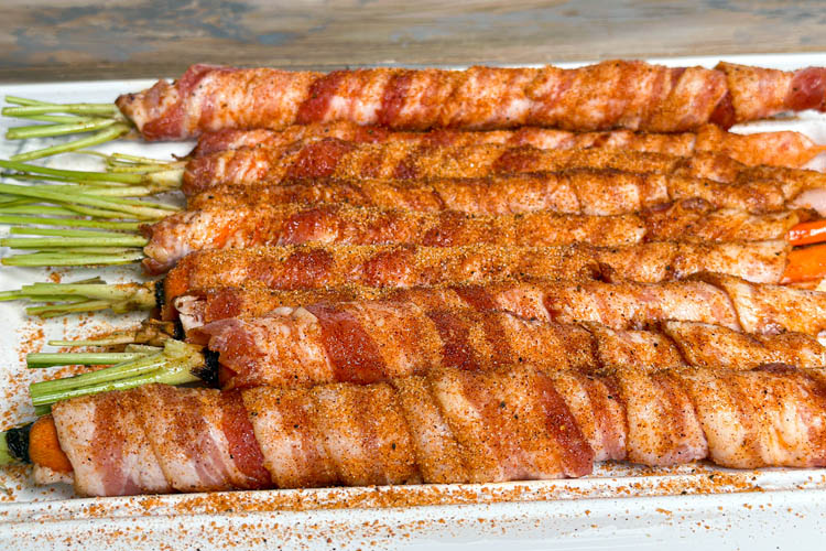 raw carrots wrapped in bacon with seasoning