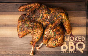 Whole smoked spatchcock turkey on a cutting board showing even browning and herb rub
