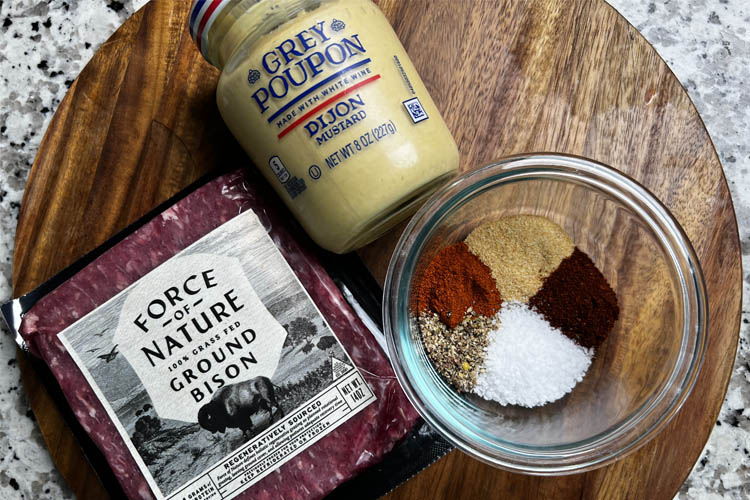 a jar of djon mustard, packet of ground bison neat and a glass jar of spices