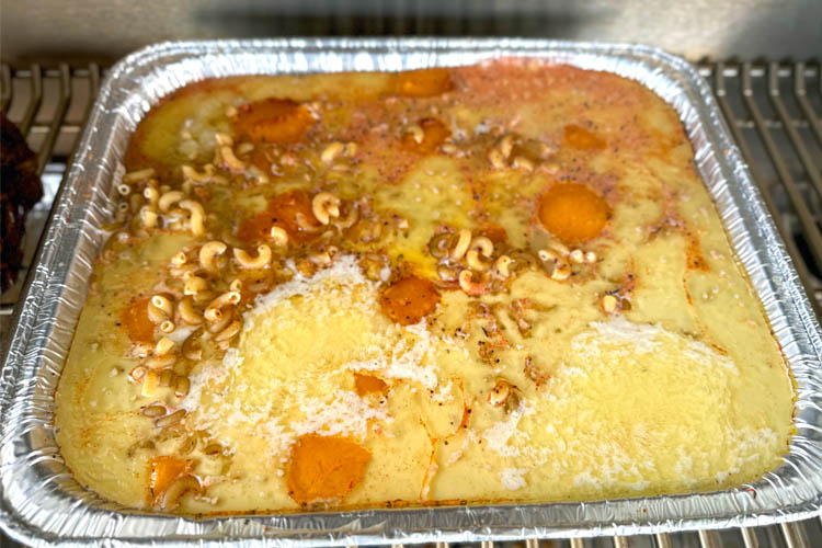 mac and cheese mixture starting to melt in a tin tray on the grill