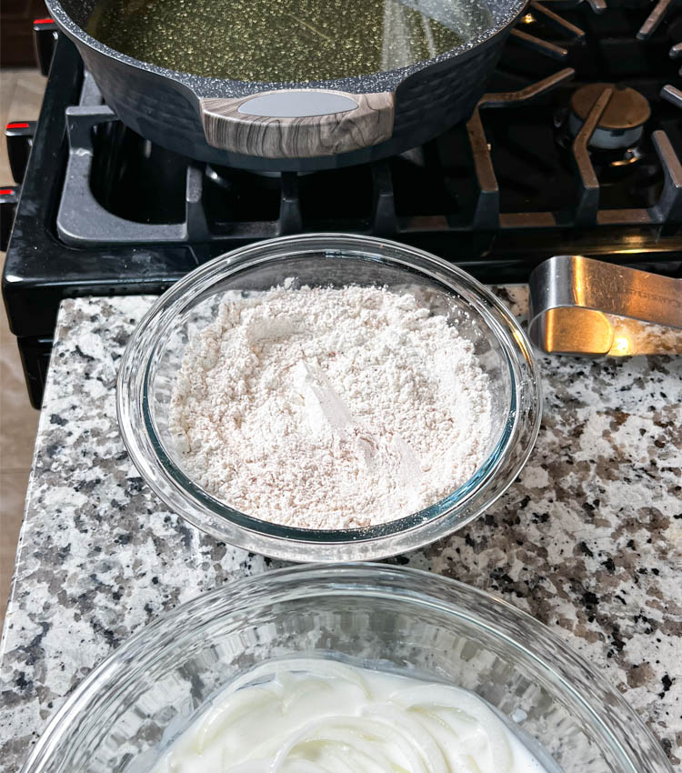 bowl onions in buttermil, bowl of flour, pot of oil on burner