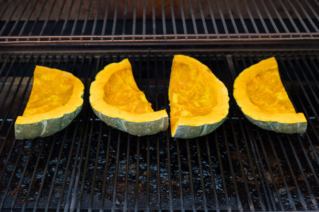 raw pumpkin quarters in the smoker