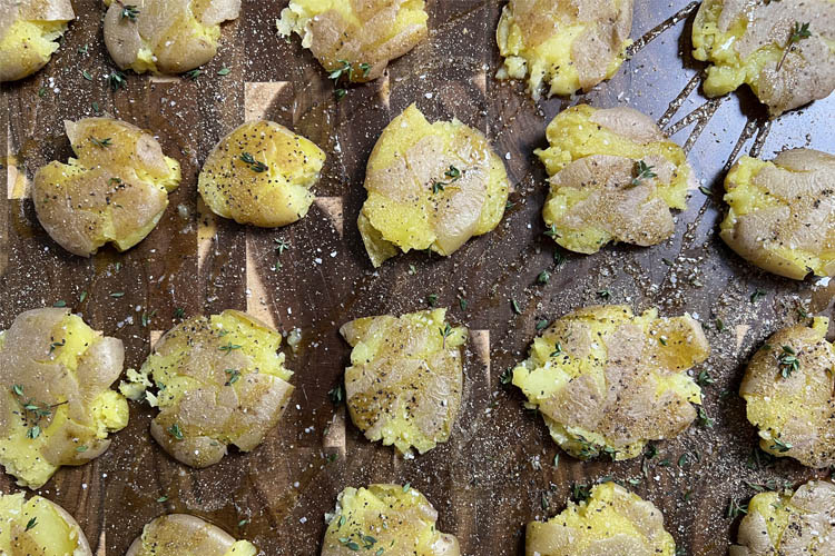 seasoned smashed potatoes on a wooden chopping board