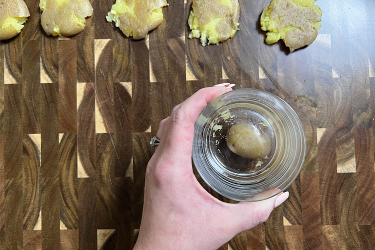 hand hold a glass that is sitting on a cooked potato