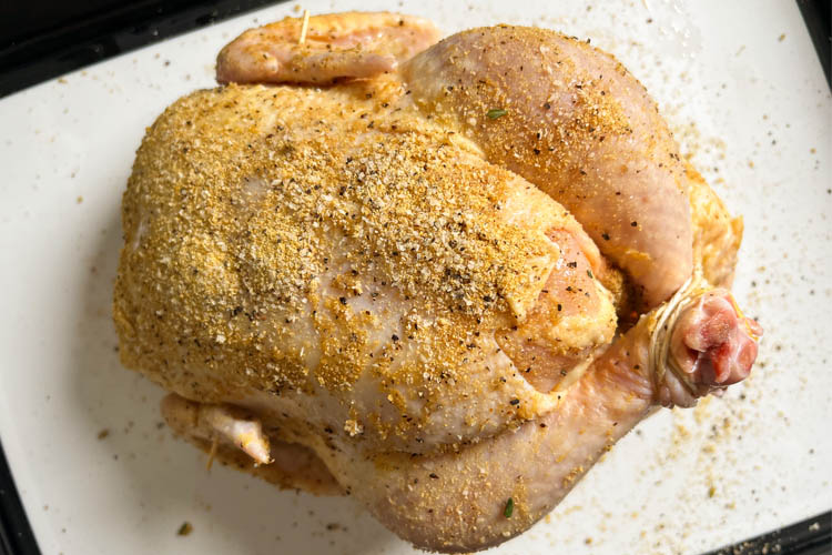 trussed seasoned chicken on a white board