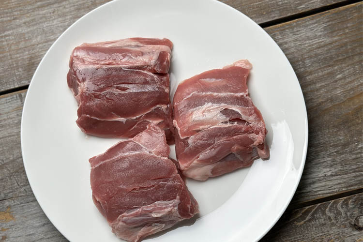unseasoned raw pig wings on a white plate