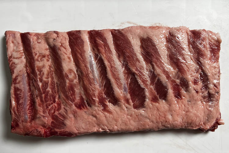 raw rack of pork ribs on a white plate